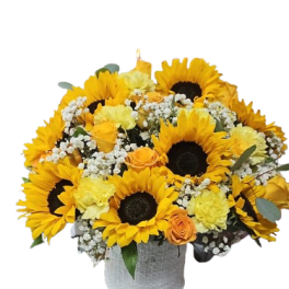 Round arrangement of sunflowers, yellow carnations, and orange roses with baby's breath in a white textured vase