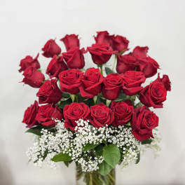 Red roses arranged in a clear glass vase with white baby's breath