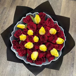 Bouquet of red roses and yellow tulips wrapped in black paper