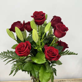 Red roses and unopened lily buds in a clear glass vase