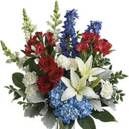Tall red, white, and blue flower arrangement with roses, lilies and hydrangea in a clear glass vase