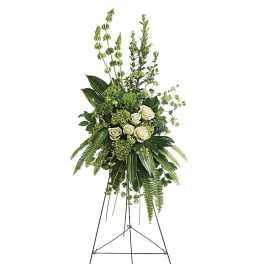 Tall green and white standing spray with white roses and lush foliage on a metal easel.