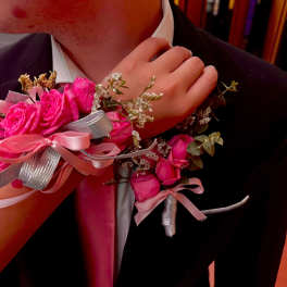 Pink rose corsage on a suit wrist with ribbon accents