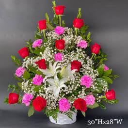 Tall basket arrangement of red roses, pink carnations, and white lilies