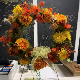 Autumn wreath with orange and yellow flowers and a pale ribbon bow