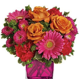 Pink and orange flower arrangement in a square glass vase