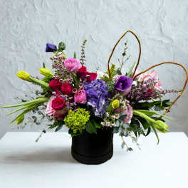 Mixed bouquet in a black hatbox with pink, purple, and yellow flowers