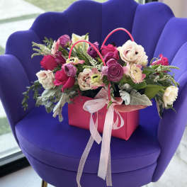 Pink and white flower arrangement in a gift bag with ribbon