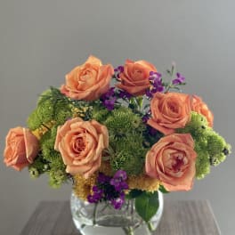 Peach roses and green chrysanthemums in a clear glass vase