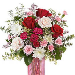 Bouquet of red, pink, and white flowers in a pink glass vase