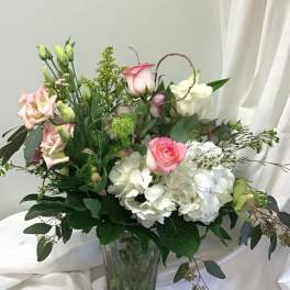 Pink and white roses with white hydrangeas in a glass vase