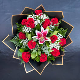 Bouquet of red roses and a pink lily with black wrap