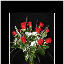 Red roses arranged in a clear glass vase with white filler flowers