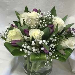Bouquet of white roses and purple tulips in a glass vase