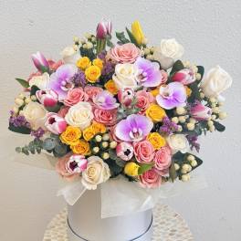 Mixed bouquet of roses, tulips, and orchids in a white hat box