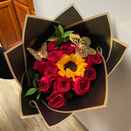 Bouquet of red roses and a sunflower in black wrapping with gold butterfly accents
