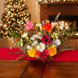 Mixed bouquet of roses and calla lilies on a table with holiday lights in the background