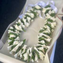 White floral lei in a gift box with a ribbon
