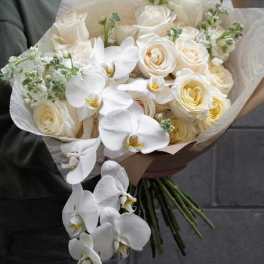 White roses and orchids in a hand-tied bouquet with cream wrapping