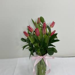 Pink tulips in a clear glass vase tied with a pink ribbon