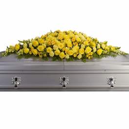 Yellow rose and carnation casket spray on a silver coffin