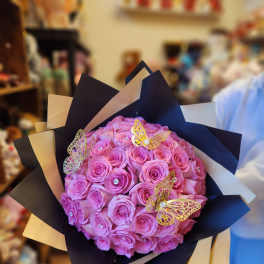 Bouquet of pink roses wrapped in black and beige paper with butterfly accents