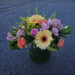 Mixed bouquet in a glass vase with yellow gerberas, pink roses, and coral carnations