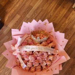 Pink rose bouquet with a gold crown and ribbon on pink wrapping