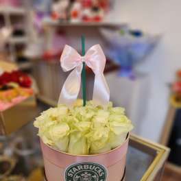 A pink box of pale yellow roses with a white ribbon bow