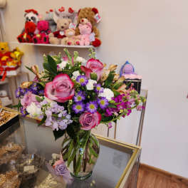 Mixed bouquet of pink roses and purple daisies in a glass vase