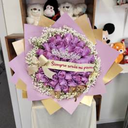 Purple rose bouquet with a tiara and ribbon reading "Siempre serías mi princesa"
