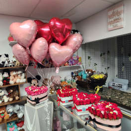 Heart-shaped balloons above boxed rose arrangements in a gift shop