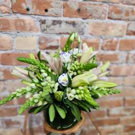 White and pale pink floral arrangement in a dark vase