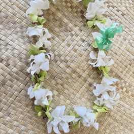 White and green flower lei on a woven mat