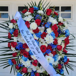 Large funeral wreath of red, white, and blue flowers with a memorial ribbon