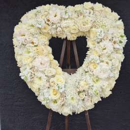 Heart-shaped white floral wreath on a stand