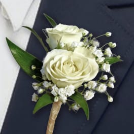 White rose boutonniere with baby's breath and green leaves
