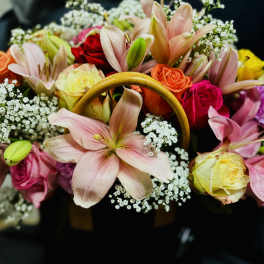 Mixed bouquet of lilies and roses in a black handbag-style container