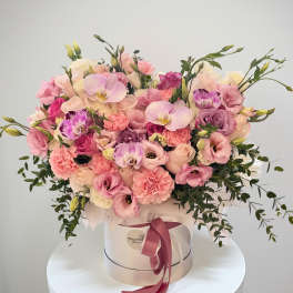 Pink and cream flower arrangement in a round hat box with ribbon