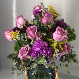 Pink roses and purple carnations in a blue glass vase