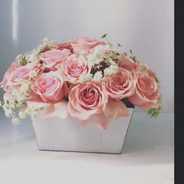 Pink roses arranged in a white wooden box with white filler flowers