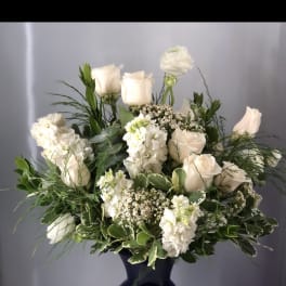 White roses and blooms arranged in a dark blue vase