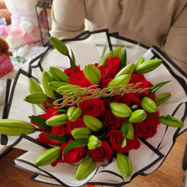 Bouquet of red roses and green lily buds with a birthday topper