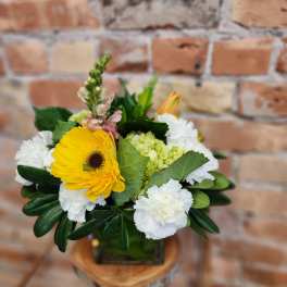 Bouquet of yellow gerbera daisies and white carnations in a glass vase
