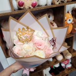 Bouquet of pale pink and white roses with a gold crown topper