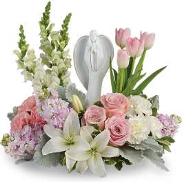 Sympathy arrangement of pink and white flowers surrounding a white angel figurine