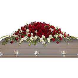 Long red and white rose casket spray arranged across a gray coffin