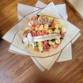 Bouquet of pink and yellow roses with a jeweled crown and ribbon
