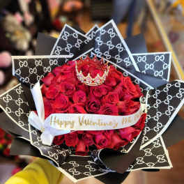 Bouquet of red roses with a small crown and patterned black wrapping