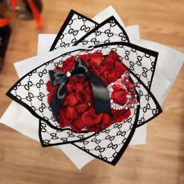 Bouquet of red roses wrapped in black-and-white patterned paper with a black ribbon
